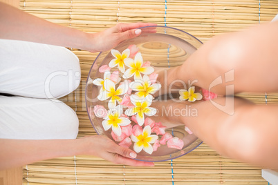 woman washing her feet in a bowl of flower