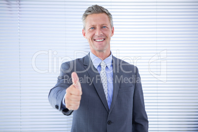 Smiling businessman giving thumbs up at the camera