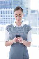 Smiling businessman texting with his mobile phone