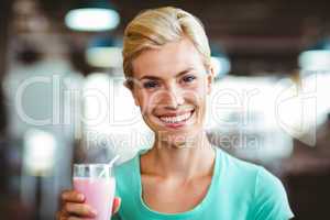 Smiling blonde woman enjoying her milkshake