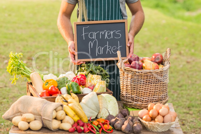 Farmer standing at his stall and holding chalkboard