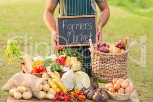 Farmer standing at his stall and holding chalkboard