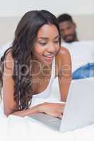 Relaxed woman using laptop on bed