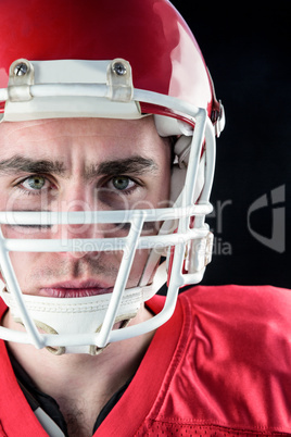 Portrait of a serious american football player taking his helmet