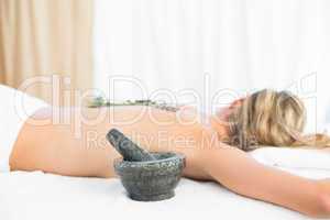 Beautiful blonde lying on massage table with mortar and pestle