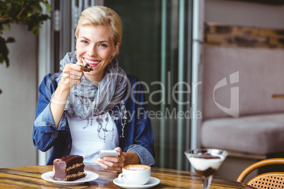 Smiling blonde enjoying a piece of chocolate cake