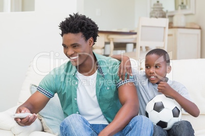 Father and son watching tv together on the couch