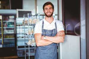 Smiling server in apron arm crossed