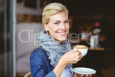 Smiling blonde enjoying a cup of cappuccino