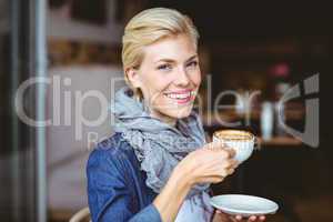 Smiling blonde enjoying a cup of cappuccino