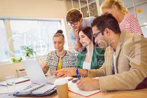 Happy creative business team using laptop in meeting