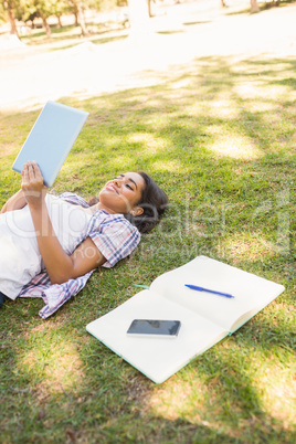 Pretty brunette relaxing in the grass and reading book