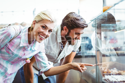 Cute couple on a date pointing cakes