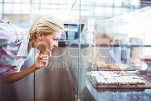 Puzzled pretty woman looking at cup cakes