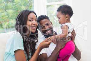 Happy couple with their baby girl on couch