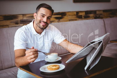 Young man having cup of coffee and eating pastry