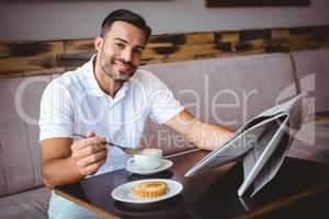 Young man having cup of coffee and eating pastry