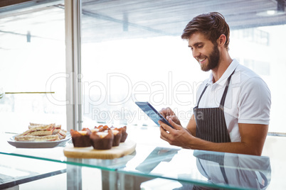 Handsome worker posing on the counter with a tablet