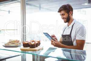 Handsome worker posing on the counter with a tablet