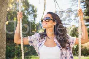 Pretty brunette swinging in park