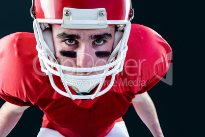 Portrait of a serious american football player taking his helmet