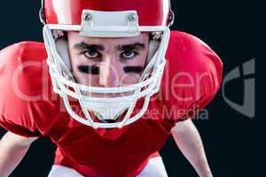 Portrait of a serious american football player taking his helmet