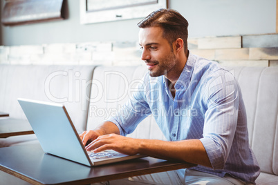 Smiling businessman using his laptop