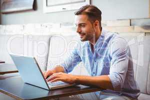 Smiling businessman using his laptop