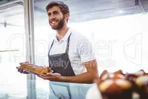 Portrait of smiling worker showing basket of bread