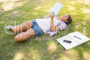 Pretty brunette relaxing in the grass and reading book