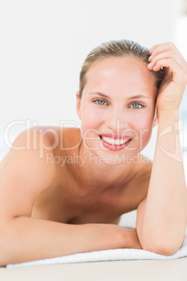 Peaceful blonde lying on towel smiling at camera