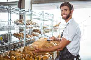 Cheerful worker standing and presenting a bread