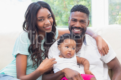 Happy couple with their baby girl on couch