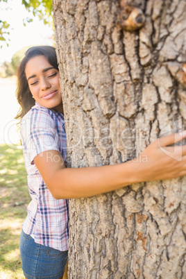 Pretty brunette hugging tree