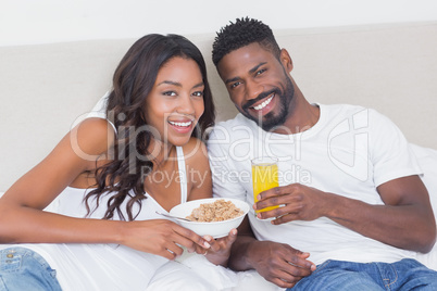 Relaxed couple in bed together eating cereal