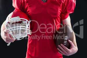 An american football player taking a helmet and ball in her hand