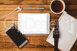 Tablet and smartphone and swatch on notepad next to cup of coffe