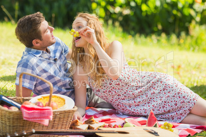 Young couple eating grapes at a picnic