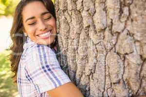 Pretty brunette hugging tree