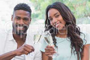 Happy couple on the couch having champagne