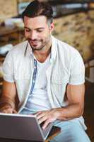 Happy young businessman working at laptop drinking coffee