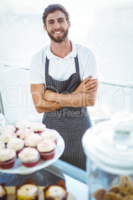 Smiling worker posing behind the counter arm crossed