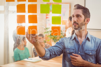 Concentrated businessman looking post its on the wall