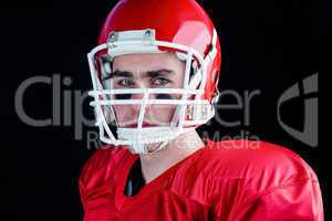 Portrait of a serious american football player taking his helmet