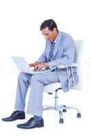 Handsome businessman sitting on a swivel chair and using his lap