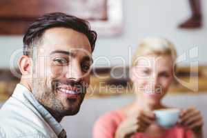 Couple with coffee cup sitting on sofa