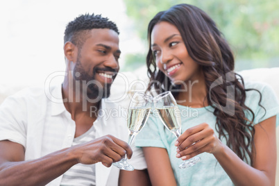 Happy couple on the couch having champagne