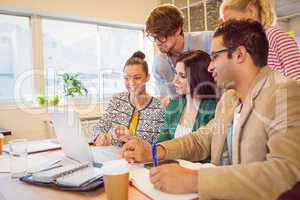 Happy creative business team using laptop in meeting