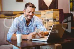 Smiling businessman sending a text message