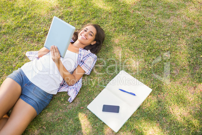 Pretty brunette relaxing in the grass and reading book